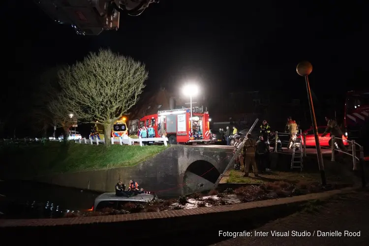 Bestelbus te water in Enkhuizen, bestuurder klimt op dak voertuig